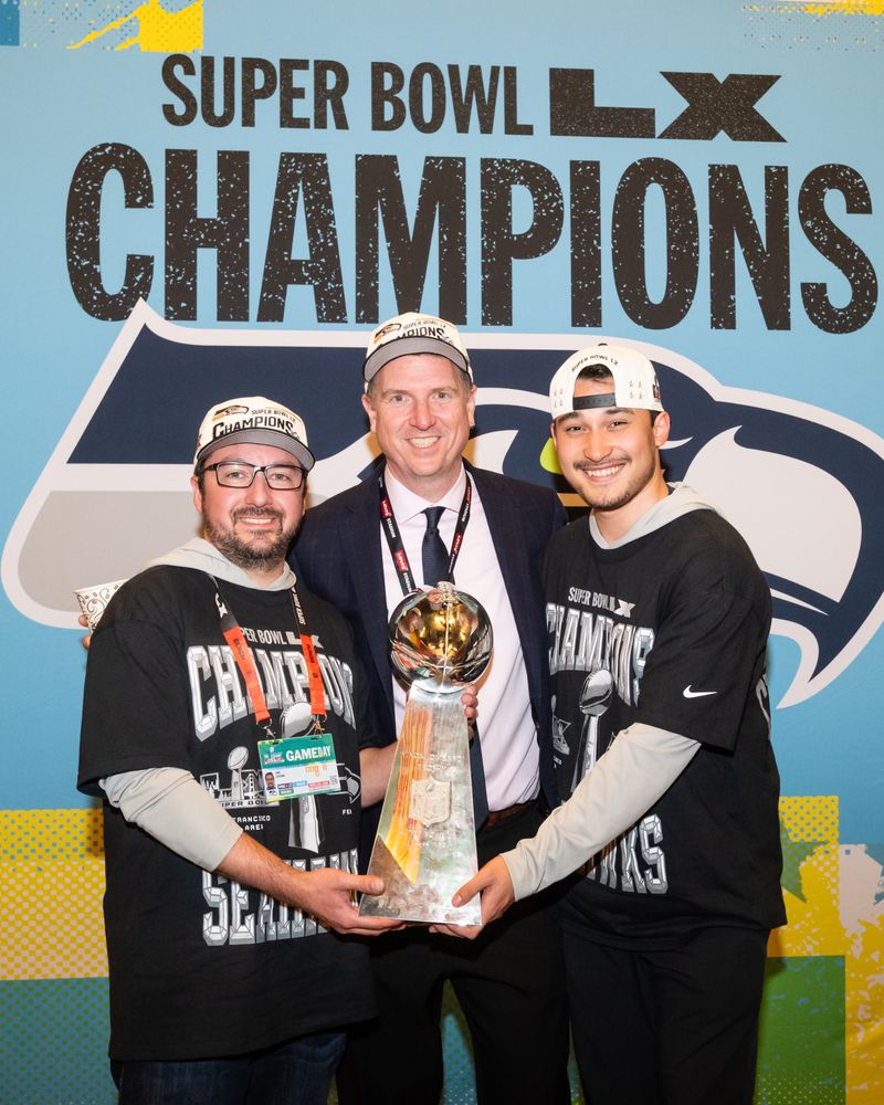 Chris Lipscomb, Nikos Mouat and Patrick Hickman with the trophy after Super Bowl LX